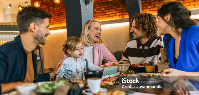 A family laughing and smiling while dining at a restaurant together