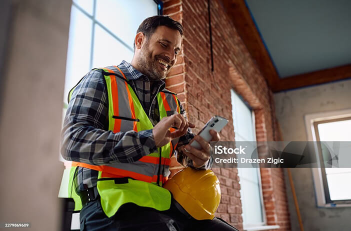 A worker in hi-vis smiling at his phone