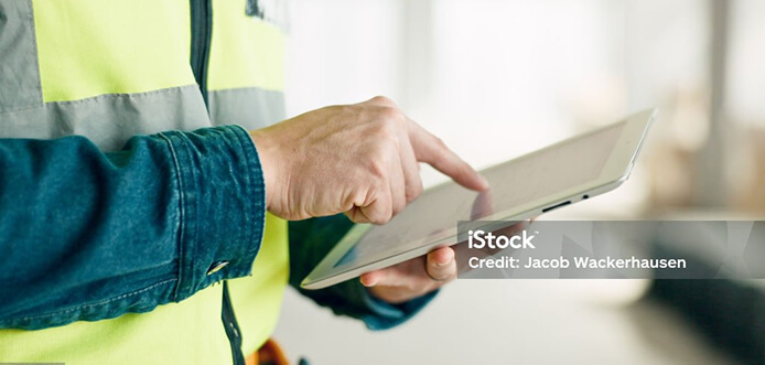 A man in hi-vis using a tablet device