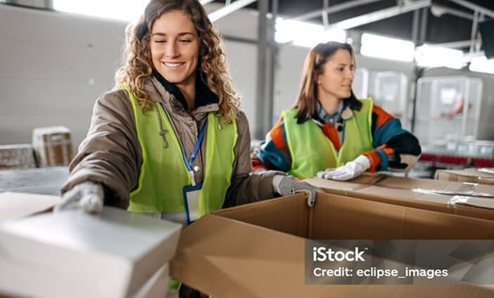 Two women packing boxes and smiling