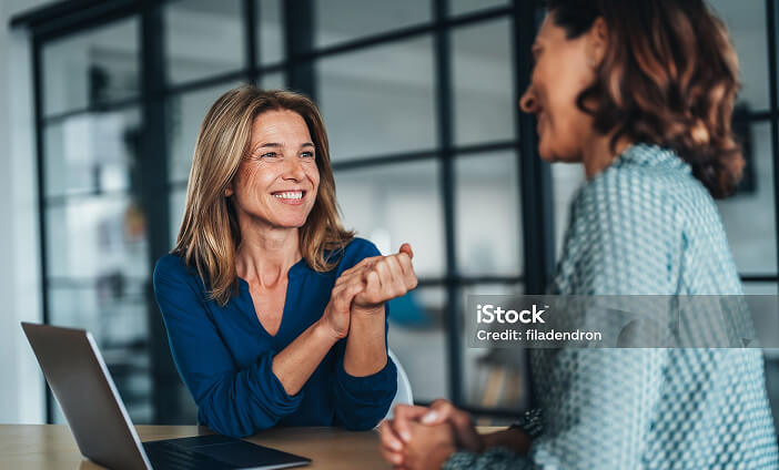 Two women smiling at each other in an office setting